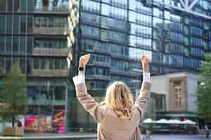 Free photo rear view of corporate woman lawyer celebrating lifting hands up and triumphing achieve goal or succ