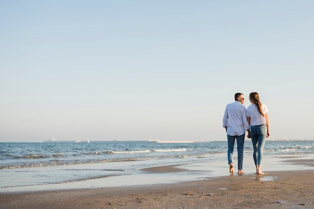 Rear view of couple walking on sandy beach