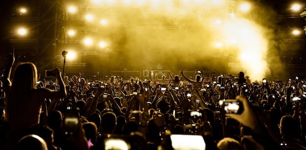 Free Photo rear view of excited fans having fun at music festival and taking pictures of stage with their smart phones copy space