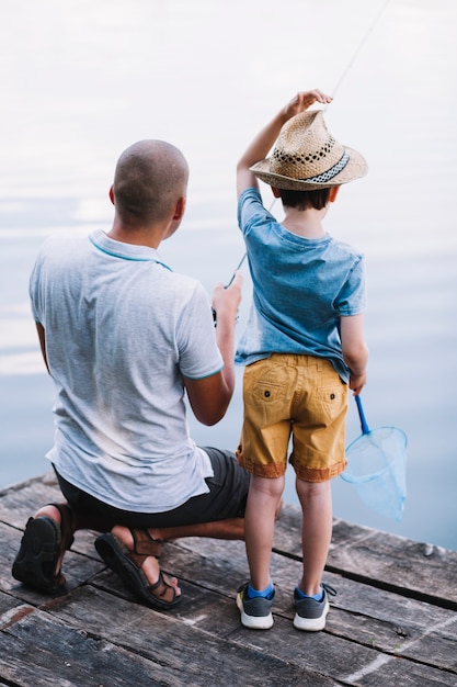 Rear view of father and boy fishing in the lake