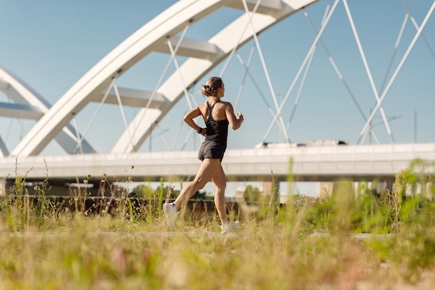 Free photo rear view of female runner jogging by the bridge in nature