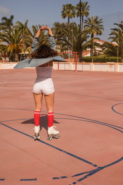 Free photo rear view of a female skater stretching her hands standing on the court