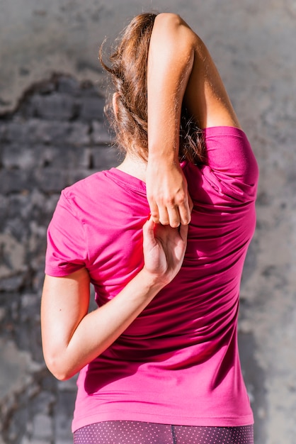 Free photo rear view of fit woman doing gomukhasana in yoga class