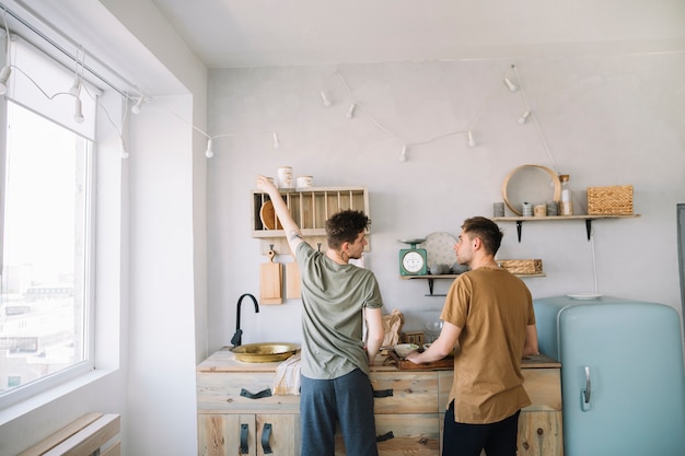 Rear view of friends preparing food in domestic kitchen