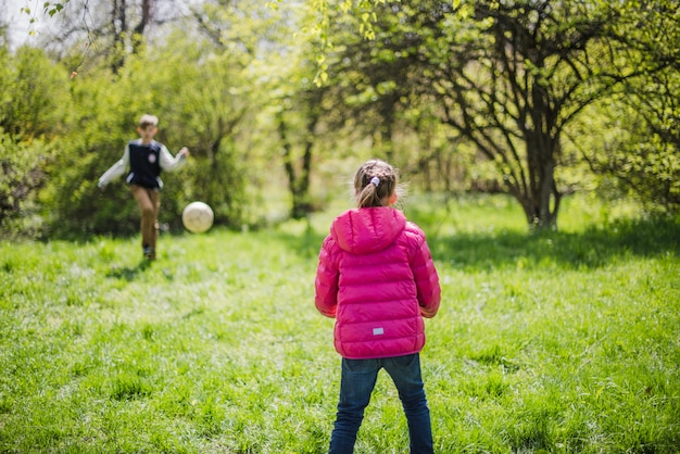 Rear view of girl playing soccer with her brother