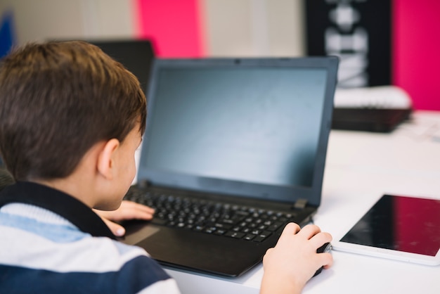 Rear view of a little boy using laptop and mouse