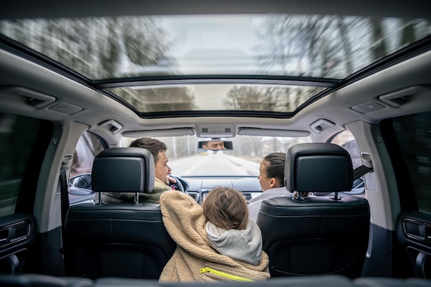 Free photo rear view little girl sitting in back seat of car during family trip