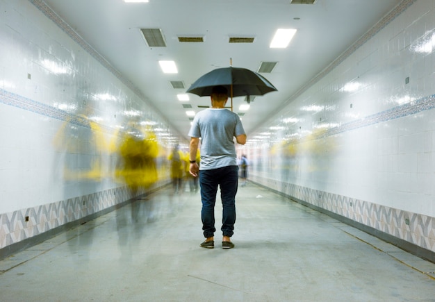 Free Photo rear view of a man holding umbrella with blurred people long exposure technique