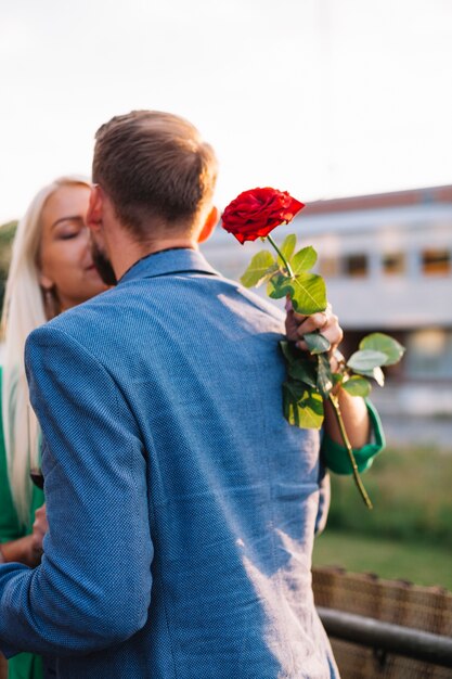 Free Photo rear view of man kissing her girlfriend holding beautiful red rose