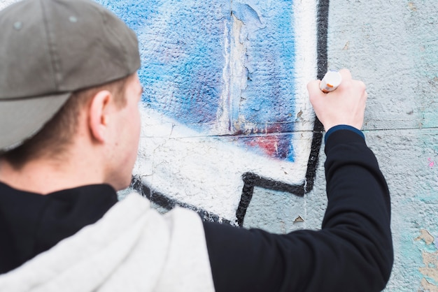 Free photo rear view of a man making graffiti outline on wall