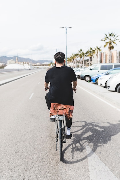 Free photo rear view of a man riding the bicycle on straight road