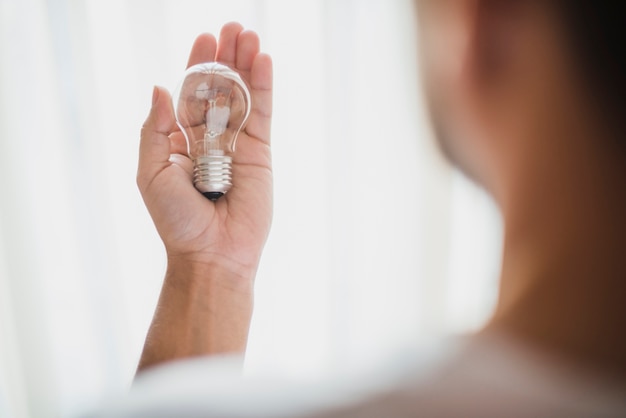 Free photo rear view of man's hand showing transparent light bulb