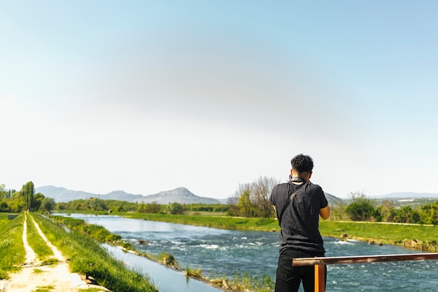 Free photo rear view of man taking picture of flowing river