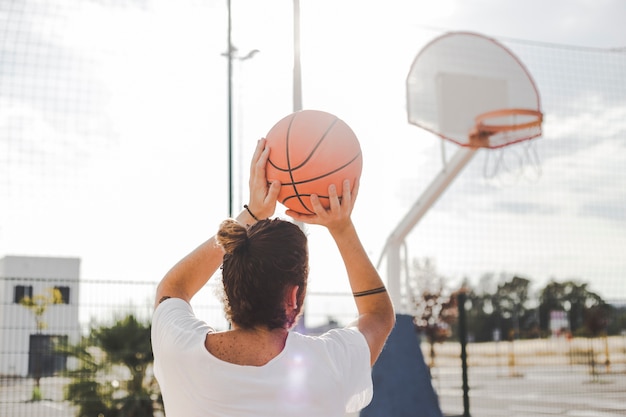 Rear view of a man throwing basketball in court