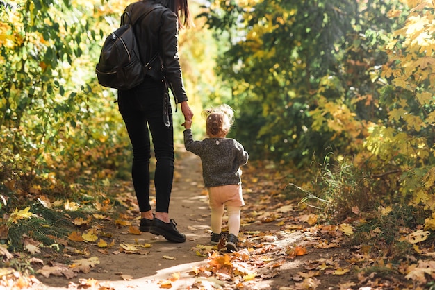 Rear view of mother and daughter walking in forest