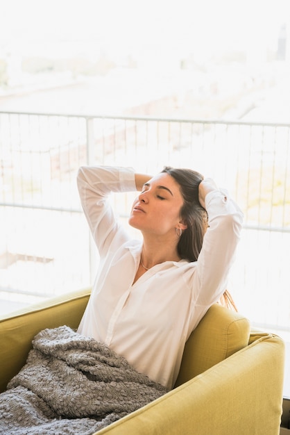 Free photo rear view of a sleepy tired young woman sitting on armchair