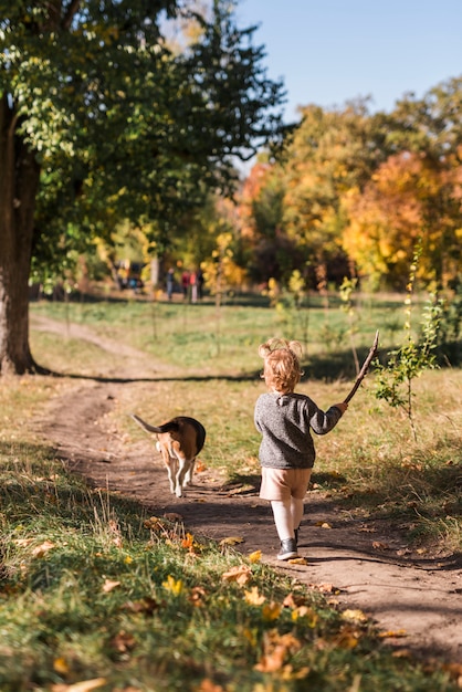 Rear view of small girl walking with her pet dog in forest trail