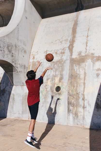 Free Photo rear view of a teenage boy practicing basketball