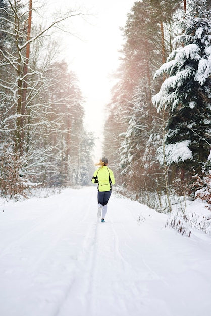 Rear view of woman running in winter forest