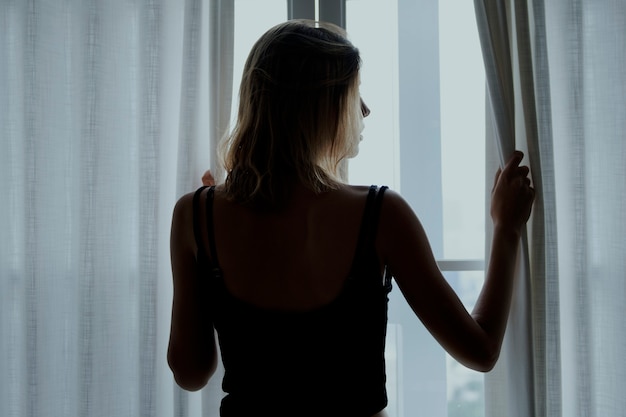 Free photo rear view of a woman standing by the window