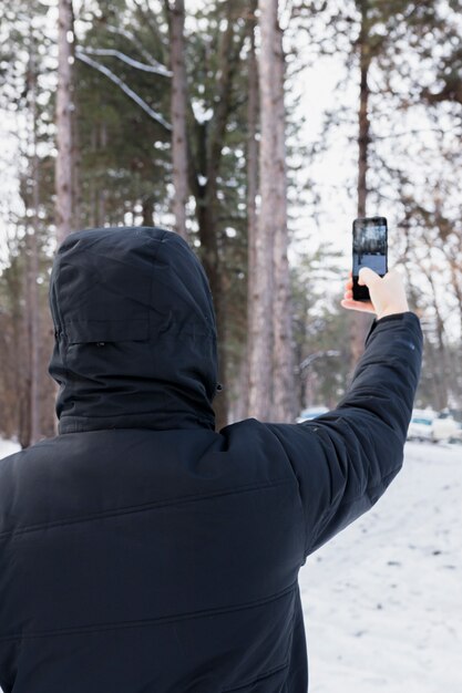 Rear view of a woman taking photograph in mobile phone