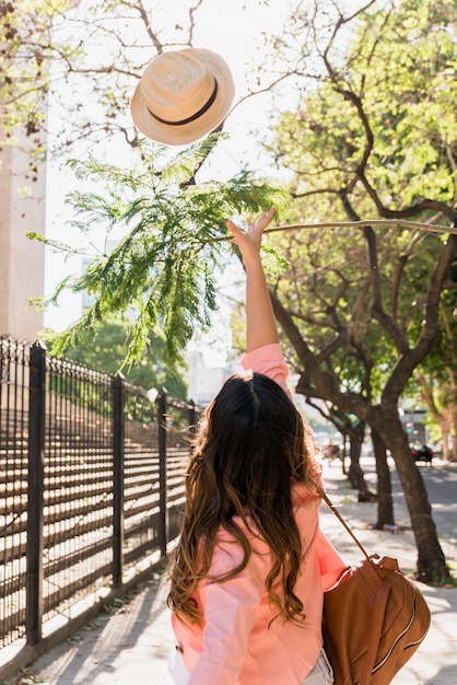 Rear view of a young female tourist throwing hat in the air