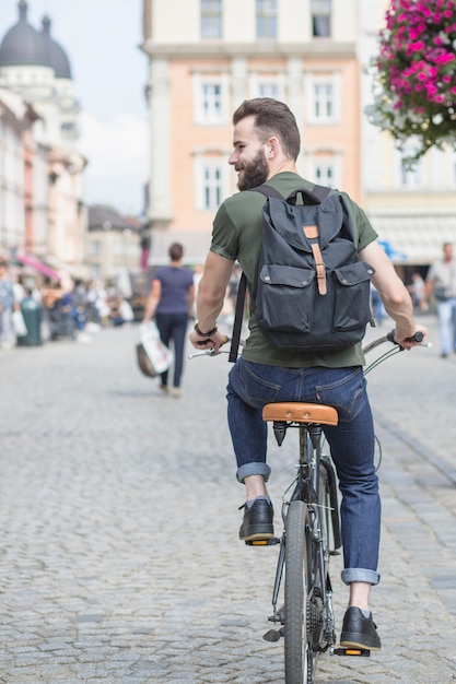 Free photo rear view of a young man riding bicycle in city