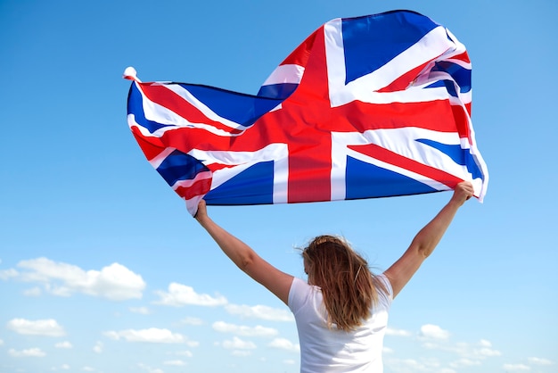 Free photo rear view of young woman waving the british flag