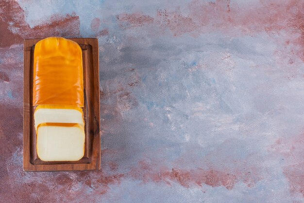 Free Photo rectangular sliced cheese on a board on the marble surface