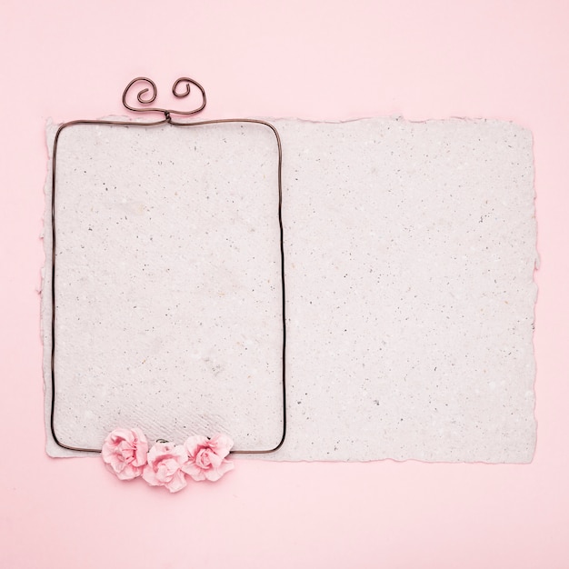 Free Photo rectangular wire frame decorated with roses on paper against pink background