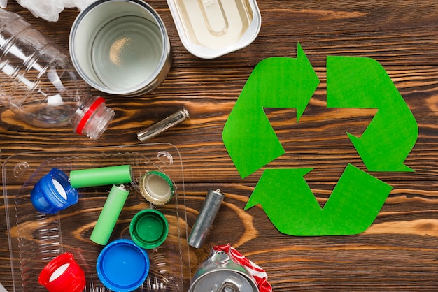 Recycle logo and various recyclable garbage on wooden desk