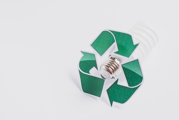 Free photo recycle symbol on compact fluorescent light bulb isolated on white background