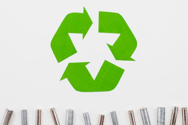 Recycle symbol and garbage batteries on grey background