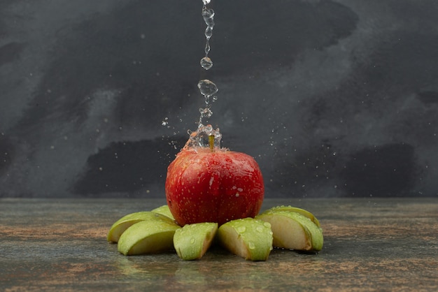 Free photo red apple with slices of apple on marble surface .