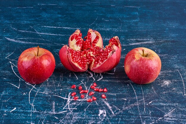 Red apples and pomegranate on blue space. 