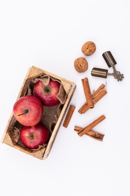 Red apples in wooden box on white surface