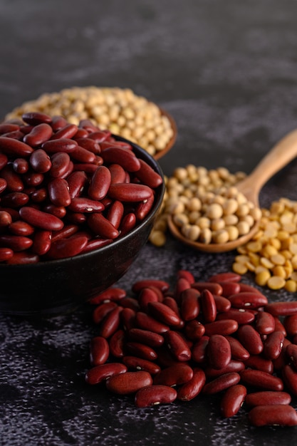 Free photo red beans in a wooden bowl on the black cement floor.