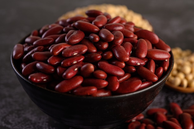 Free photo red beans in a wooden bowl on the black cement floor.