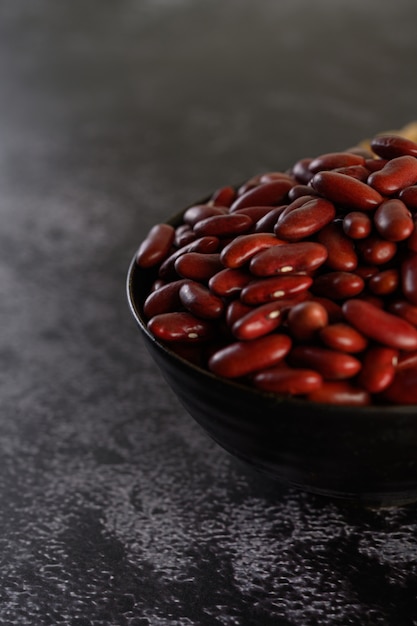 Red beans in a wooden bowl on the black cement floor.