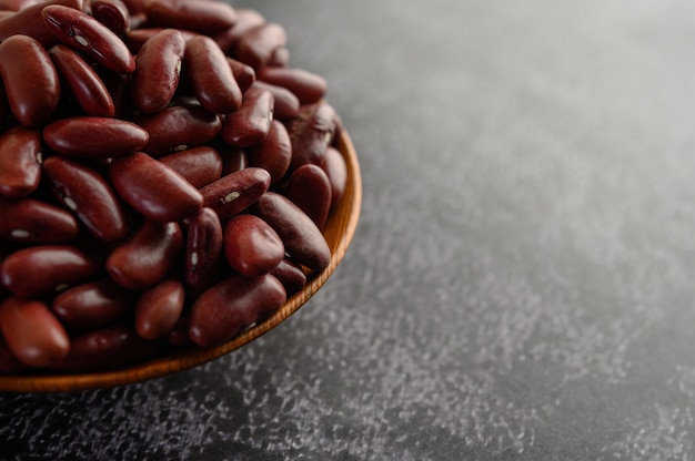 Red beans in a wooden bowl on the black cement floor.