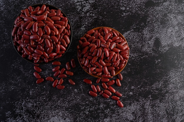 Free photo red beans in a wooden bowl on the black cement floor.