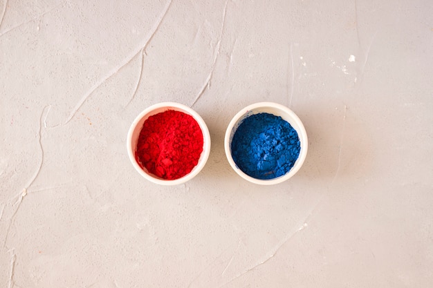 Free Photo red and blue holi colored powder in the white bowl on backdrop