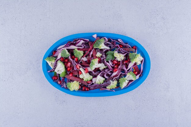 Red cabbage and broccoli salad mixed with pomegranate arils on marble background. High quality photo