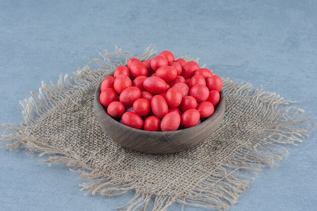 Red candies in the cup on the trivet, on the marble table. 