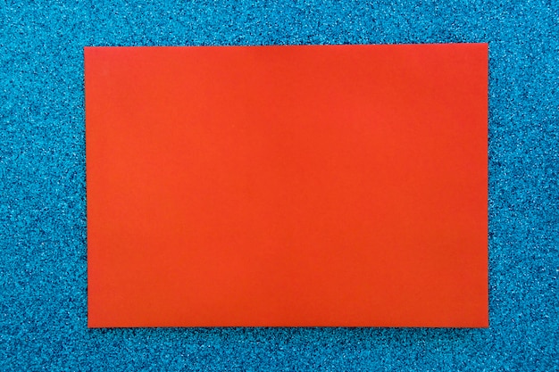 Red cardboard paper on blue glitter background