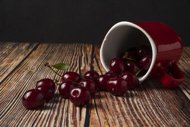 Red cherries out of a white cup on the table