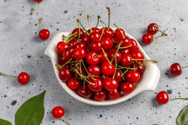 Red cherries in plate bowl on gray table