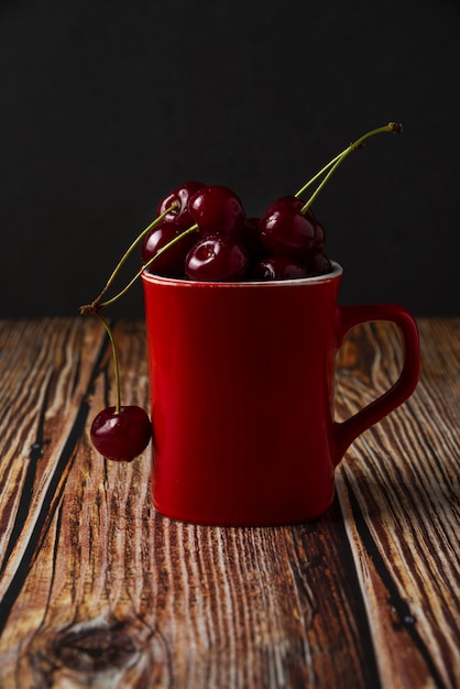 Free Photo red cherries in a red cup on the table