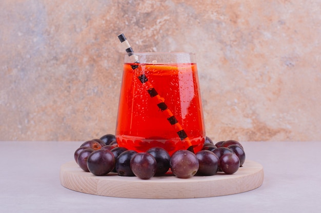 Free photo red cherry berries with a glass of juice on grey.