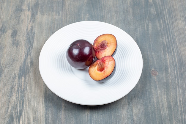 Free Photo red cherry plum isolated on a white plate